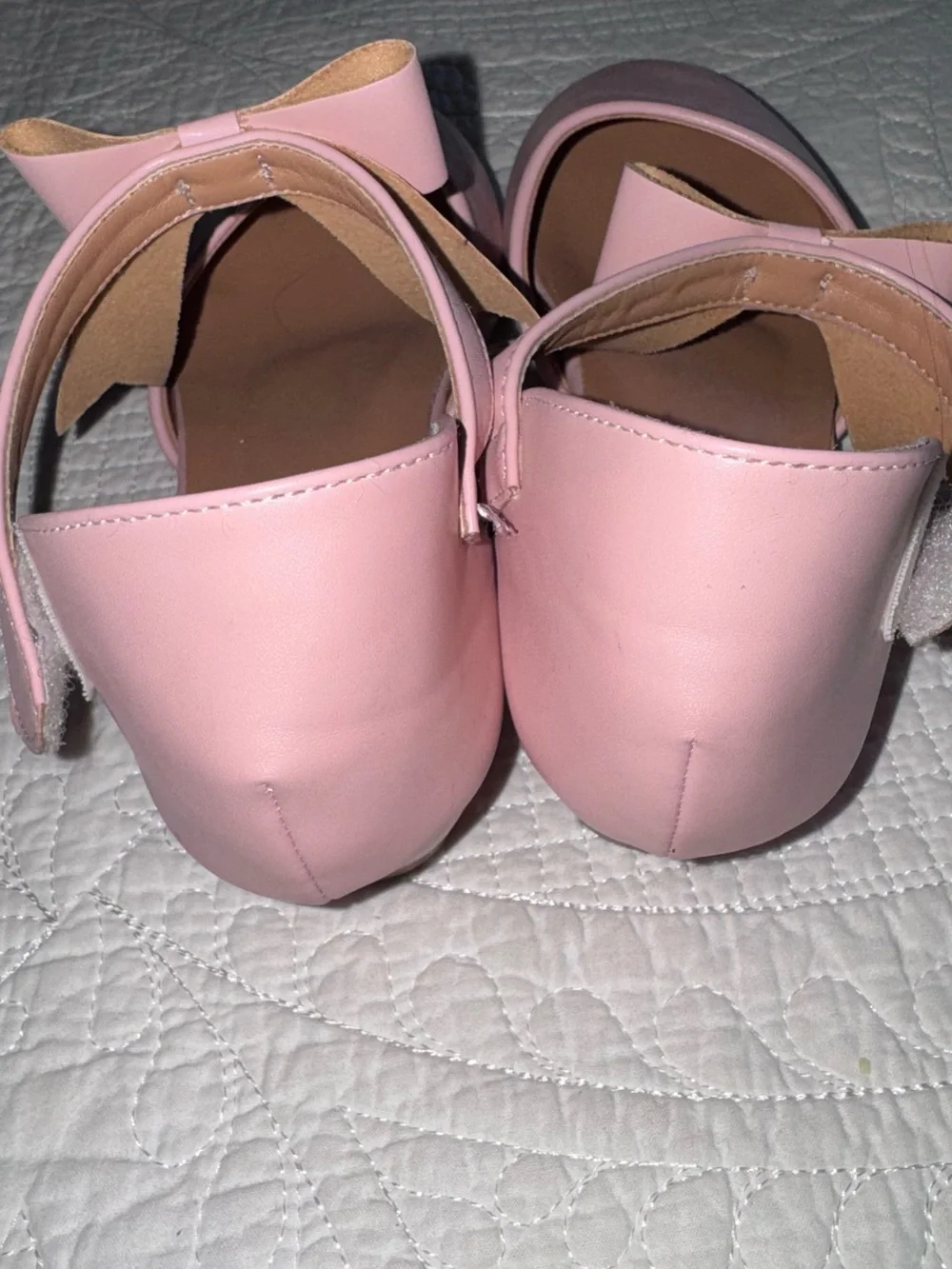 These pastel pink Mary Janes feature a delicate crisscross ankle strap adorned w